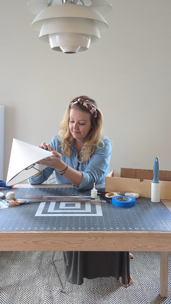 lamp shade maker, Krista Hyde, at her work table with a cone shaped lamp shade