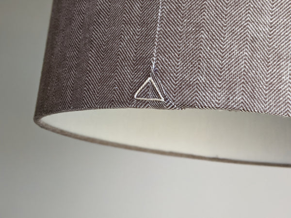 Close-up of the back seam of a herringbone fabric lamp shade with a triangle stitch detail on the bottom