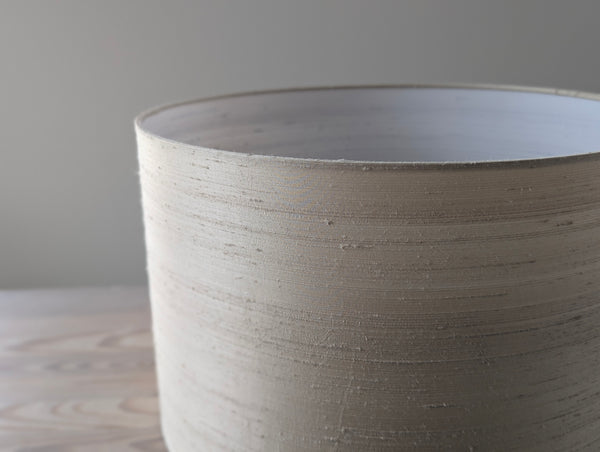 Close-up of a textured  dupioni silk lamp shade on a neutral background