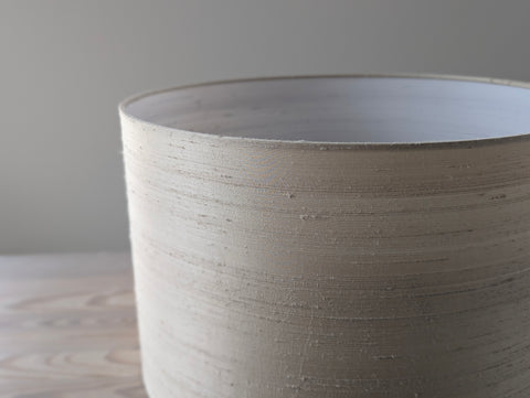 Close-up of a textured  dupioni silk lamp shade on a neutral background