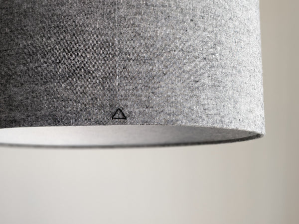 back and white woven fabric lampshade with a black triangle stitch detail on the back seam on a neutral background