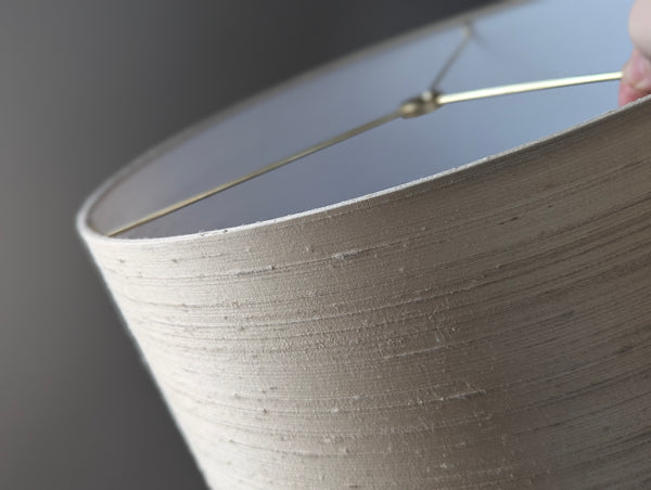 Close-up of a cream silk lampshade with a dark background