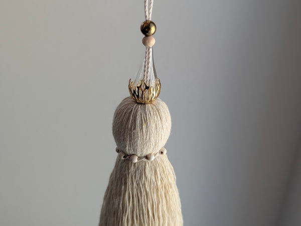 Decorative tassel with brass and glass beads on a plain background