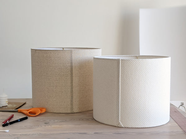 Speckled Oatmeal cotton fabric lampshade with brass hardware against a blurred background