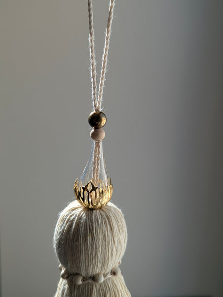 Decorative tassel with brass and glass beads on a plain background