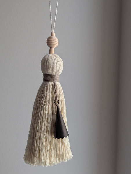 Decorative tassel with beige and black elements on a gray background