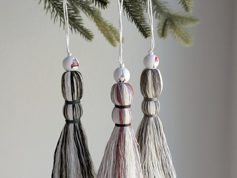 Three decorative tassel ornaments hanging from a tree branch