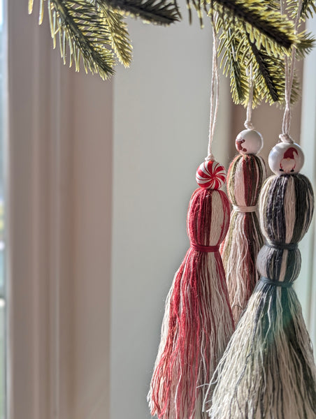 Three tassel ornaments hanging from a Christmas tree branch.