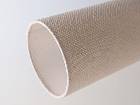 Close-up of a textured, crosshatch fabric lamp shade in a natural colorway on a neutral background