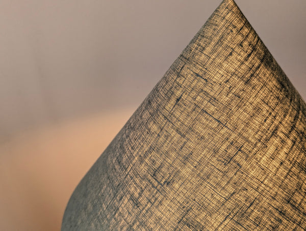 close up of the green linen fabric lamp shade with light shining through it from having the lamp turned on