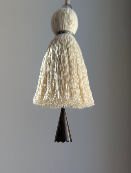 Decorative cotton tassel and dark brown bell on a gray background