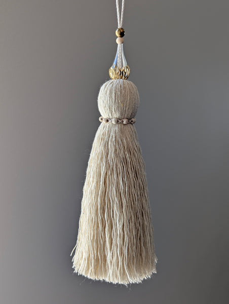 Decorative tassel with brass and glass beads on a plain background