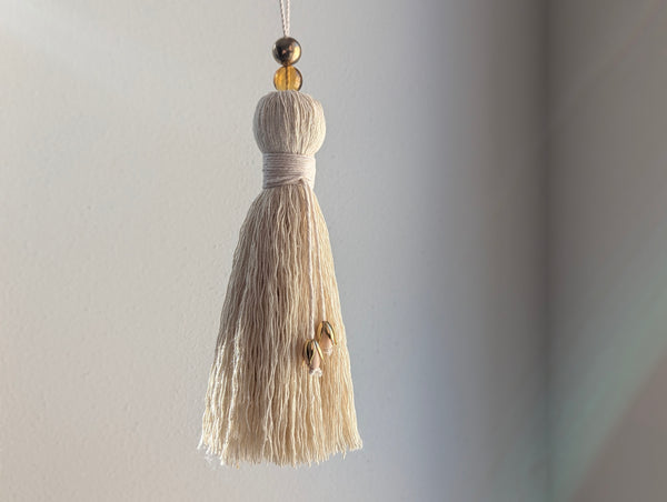 Decorative tassel with beads on a plain background