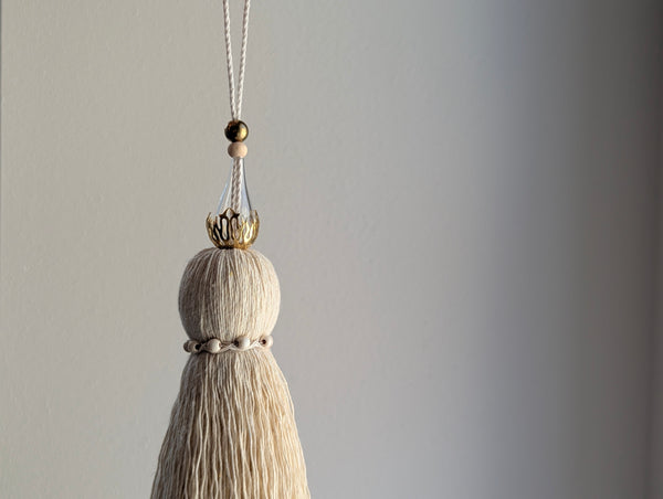 Decorative tassel with beads on a plain background