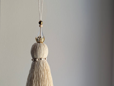 Decorative tassel with beads on a plain background