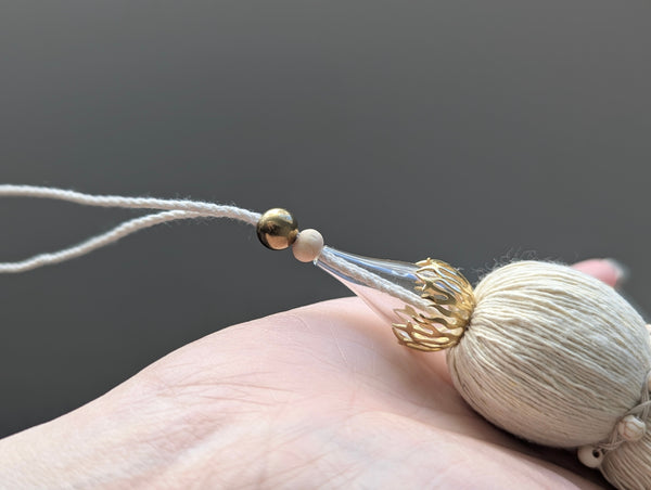 Decorative tassel with brass and glass beads on a plain background