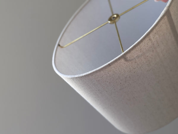 Close-up of a natural colored, textured lampshade in an oval shape with brass hardware
