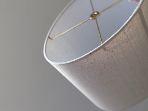 Close-up of a natural colored, textured lampshade in an oval shape with brass hardware