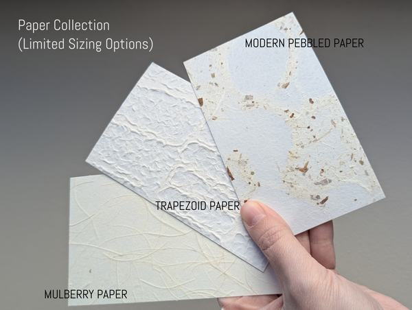Three types of paper lamp shade samples held by a hand against a gray background