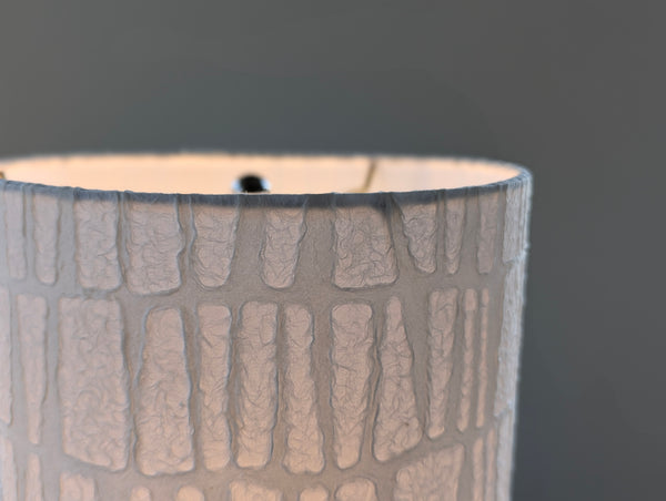textured paper lamp shade with light from the light bulb shining through the paper
