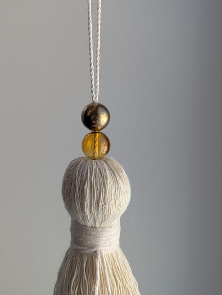 Tassel with two beads on a gray background