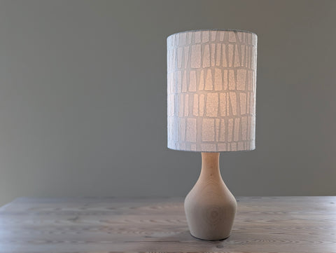 white textured paper lamp shade with geometric pattern on a wooden table lamp