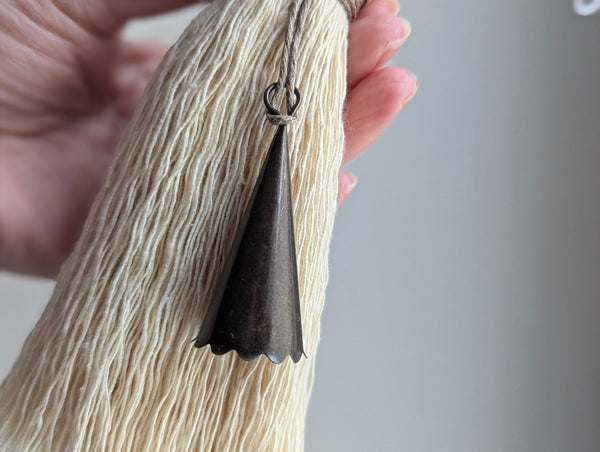 Hand holding a tassel with a bell against a neutral background