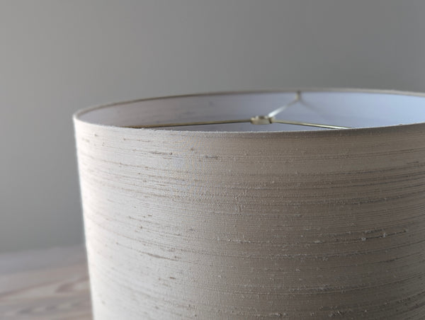 Close-up of a cream silk lampshade against a neutral background