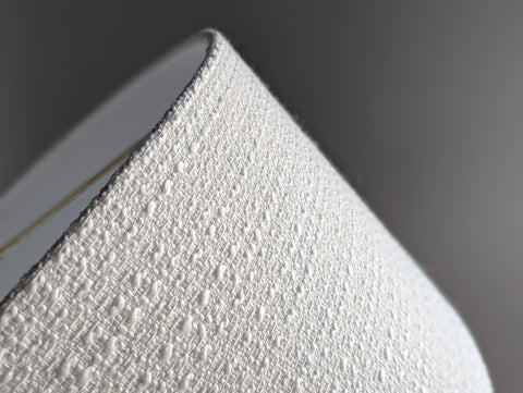 close up on an ivory boucle lamp shade with brass hardware 