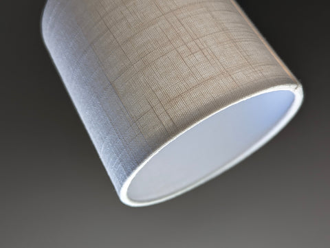 Close-up of a small drum lampshade made of white linen fabric 