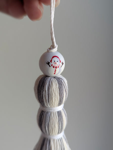 Decorative tassel gift tag with a snowman design on a plain background