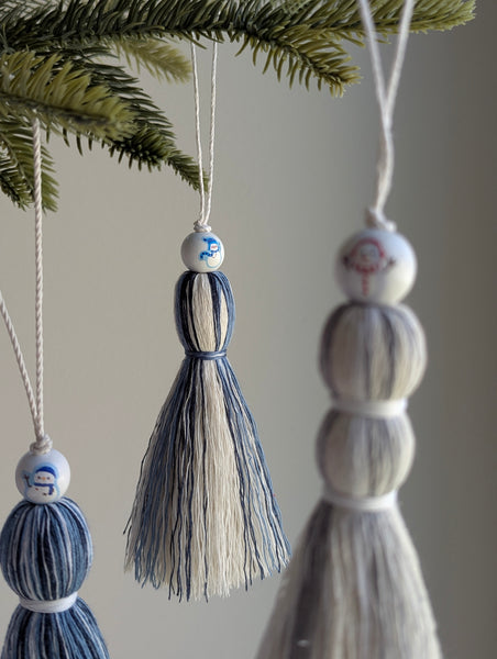 Decorative tassels hanging from a Christmas tree with snowman beads