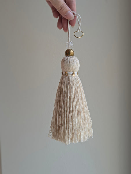snowy white tassel in a natural cotton color with brass accents and a handblown glass bead
