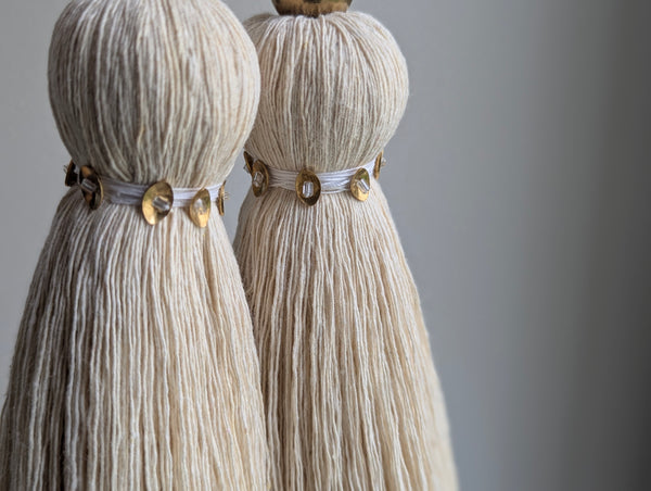 snowy white tassel in a natural cotton color with brass accents and a handblown glass bead