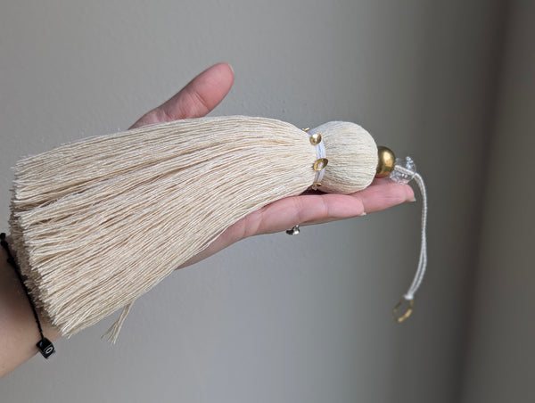 snowy white tassel in a natural cotton color with brass accents and a handblown glass bead
