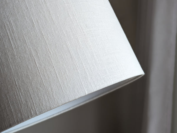 Close-up of a white linen textured lampshade on a neutral background