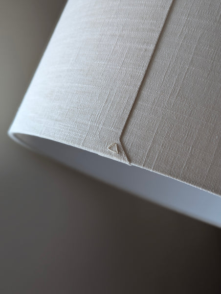 Close-up of a drum lampshade made of white linen fabric with a triangle on the back seam for Ud Form