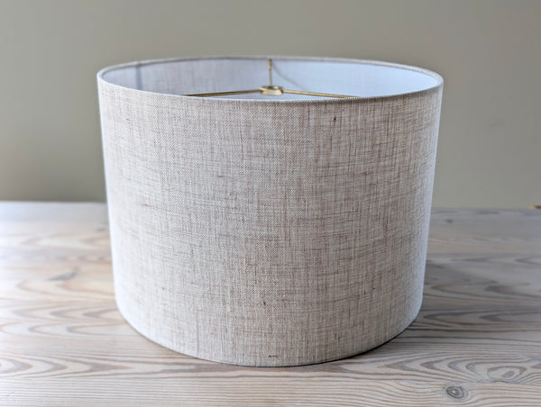 linen lamp shade with brass hardware sitting on a light wood table