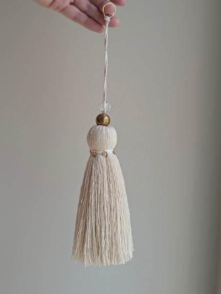 snowy white tassel in a natural cotton color with brass accents and a handblown glass bead