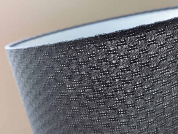 Close-up of a textured gray lamp shade with a blurred background