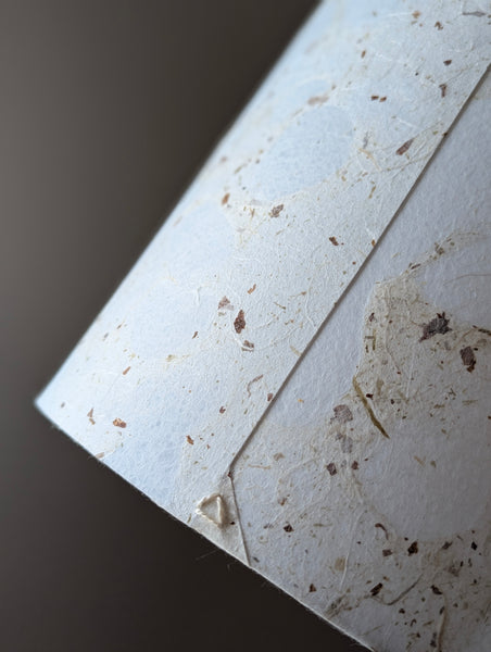 modern pebbled paper lampshade with textured paper in white and cream colorway and triangle in the back seam