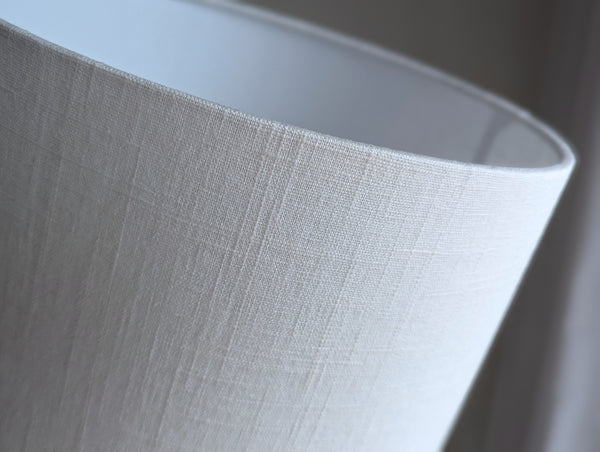 Close-up of a white linen textured lamp shade against a neutral background