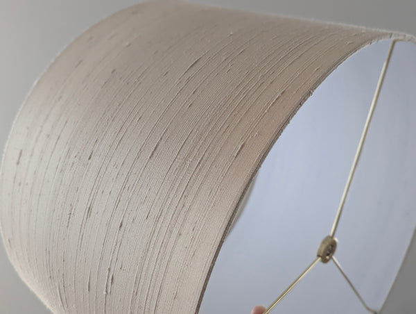 Close-up of a cream silk lampshade with a white background