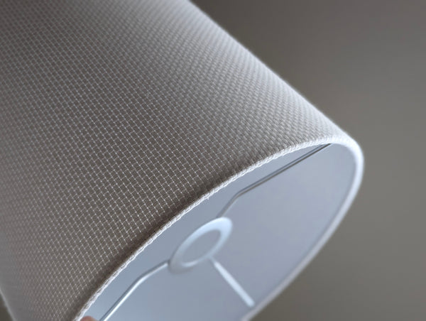 Close-up of a white textured lampshade in Bright White Crosshatch fabric with euro fitter hardware  against a soft gray background