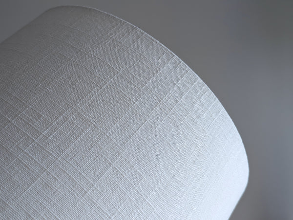 Close-up of a white linen fabric lampshade against a neutral background