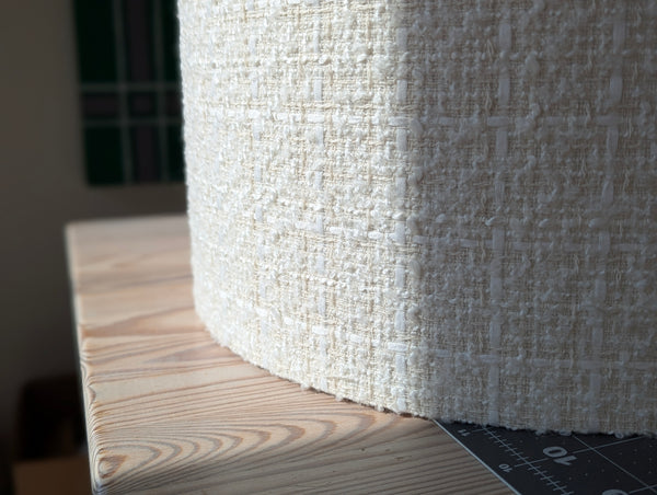 boucle tween lamp shade in ivory on a wooden work table in the sunlight