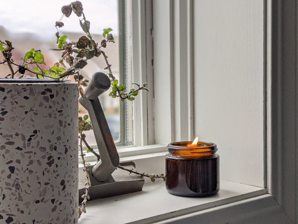 an amber glass candle lit on a white windowsill