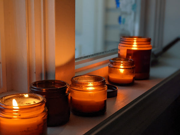 amber candles lit on a windowsill on a cozy fall evening