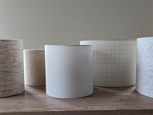 Set of modern lamp shades with textured surfaces on a wooden surface.