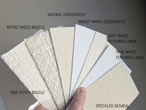 Hand holding fabric swatches labeled with different textures and patterns on a gray background